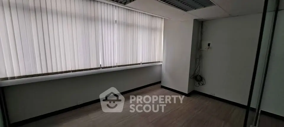 Spacious office room with large window and vertical blinds, ideal for professional workspace.