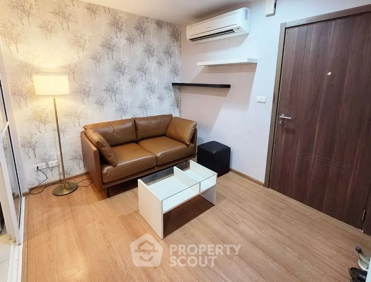 Cozy living room with modern decor, featuring a brown leather sofa and stylish wallpaper.