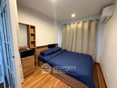 Cozy bedroom with wooden flooring and modern furnishings in a stylish apartment.