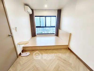 Modern minimalist room with large window and city view, featuring wooden flooring and built-in storage.