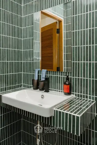 Modern bathroom with stylish green tile design and sleek white sink