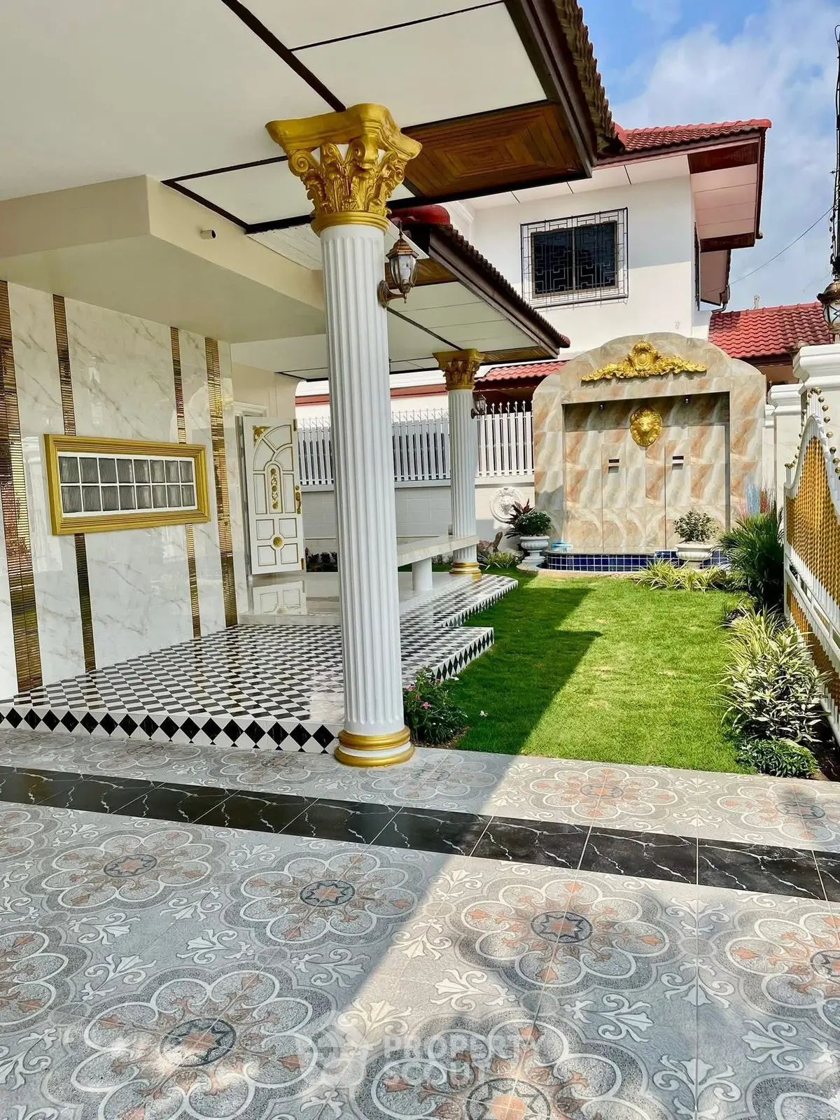 Luxurious home exterior with elegant columns, ornate tiles, and lush garden, showcasing opulent architectural design.