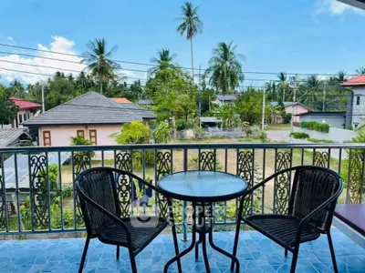 Charming balcony with outdoor seating and scenic view of lush greenery and palm trees.