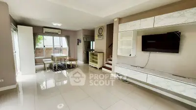 Spacious modern living room with sleek TV setup and dining area, perfect for family gatherings.