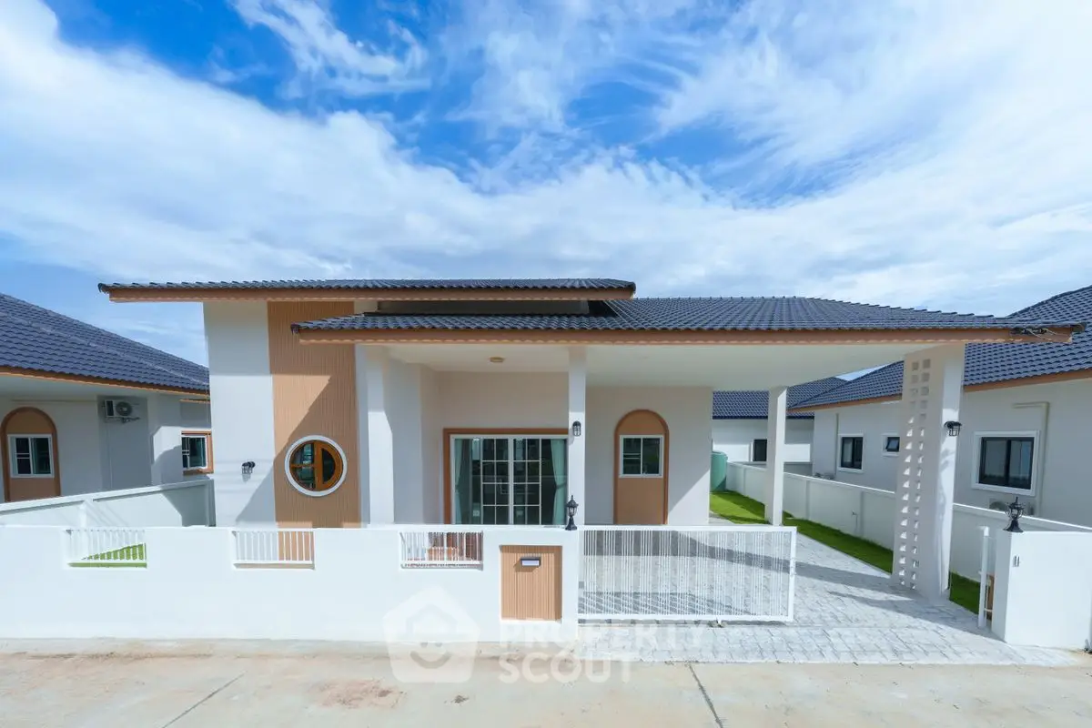 Modern single-story house with stylish architecture and spacious front yard under a clear blue sky.
