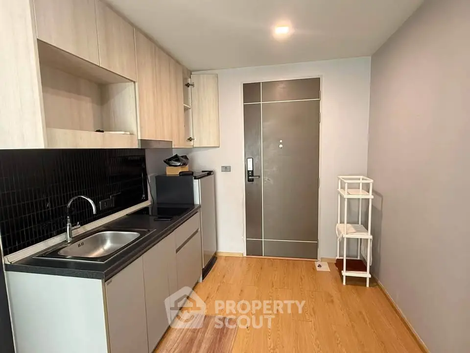 Modern compact kitchen with sleek cabinetry and wood flooring in a cozy apartment.