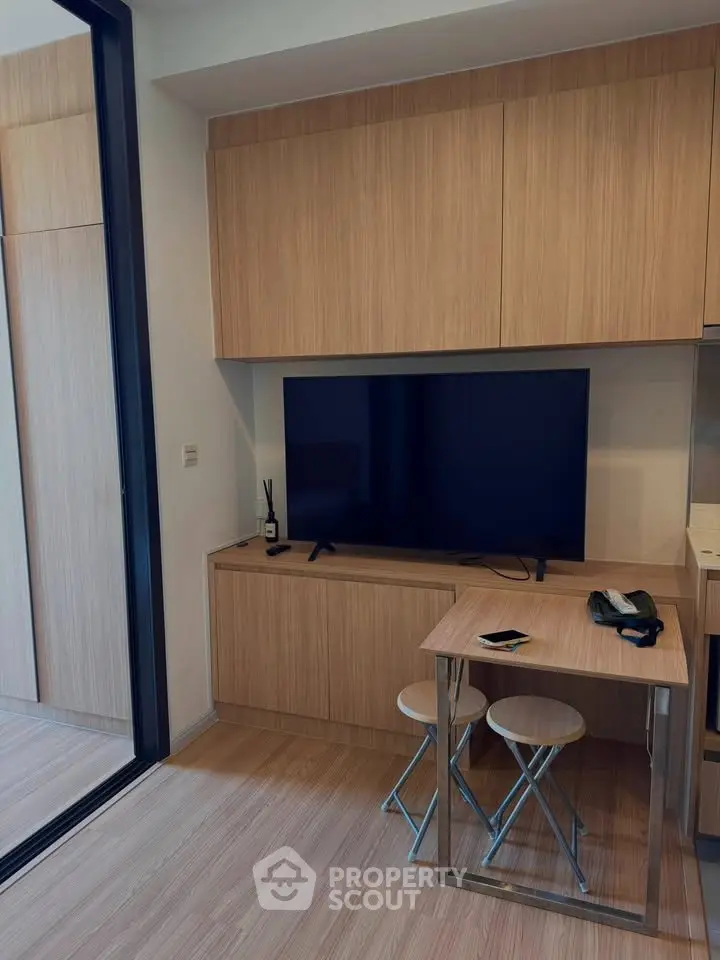 Modern compact living room with sleek wooden cabinetry and flat-screen TV, ideal for urban living.