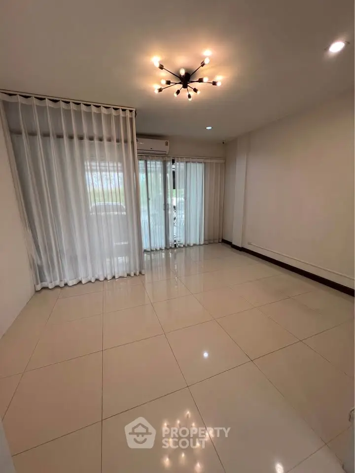 Spacious empty living room with modern lighting and large windows.