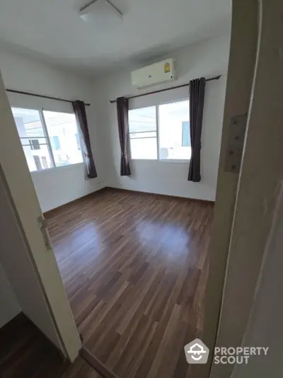 Spacious empty bedroom with wooden flooring and large windows