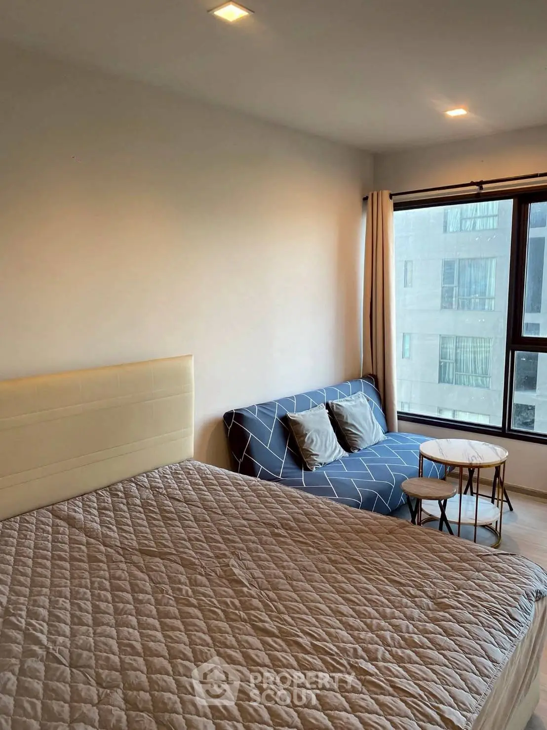 Modern bedroom with cozy bed and stylish seating area near large window