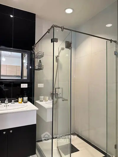 Modern bathroom with glass shower enclosure and sleek vanity in contemporary apartment.