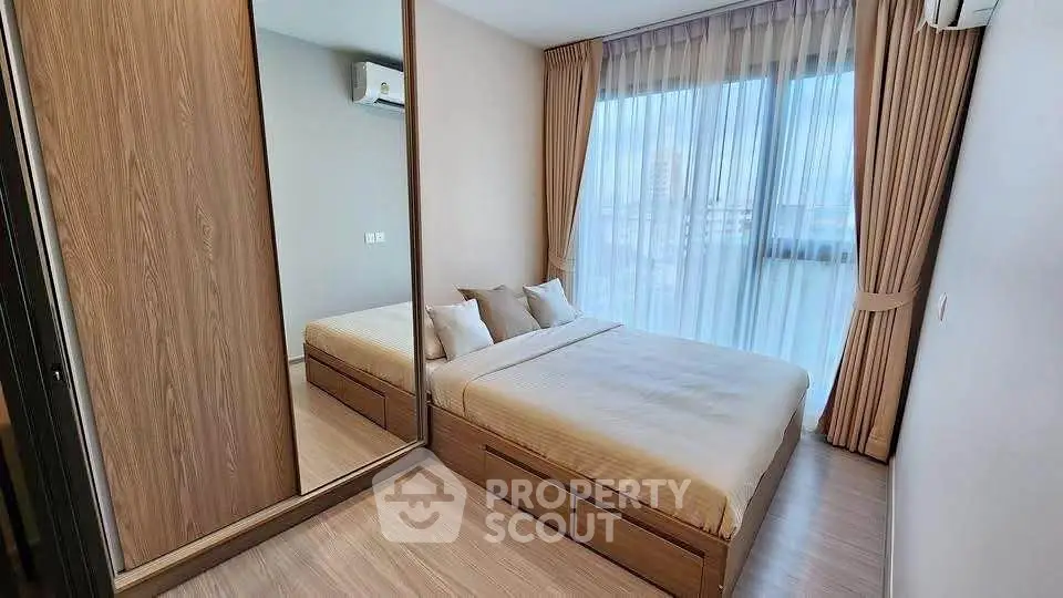 Modern bedroom with large mirrored wardrobe and floor-to-ceiling windows in a stylish apartment.