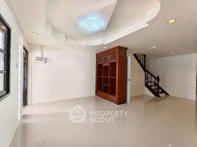 Spacious living room with elegant staircase and built-in wooden shelving