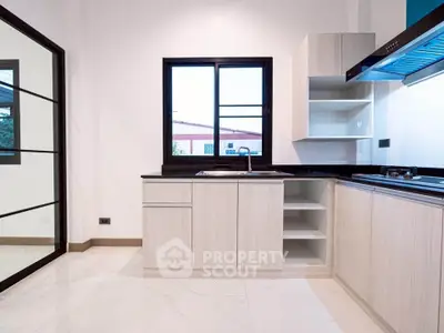 Modern kitchen with sleek cabinetry and large window for natural light.