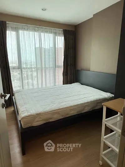 Modern bedroom with large window offering city view, featuring a comfortable bed and sleek design.
