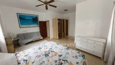 Spacious bedroom with floral bedding, ceiling fan, and ample storage in a bright, airy setting.