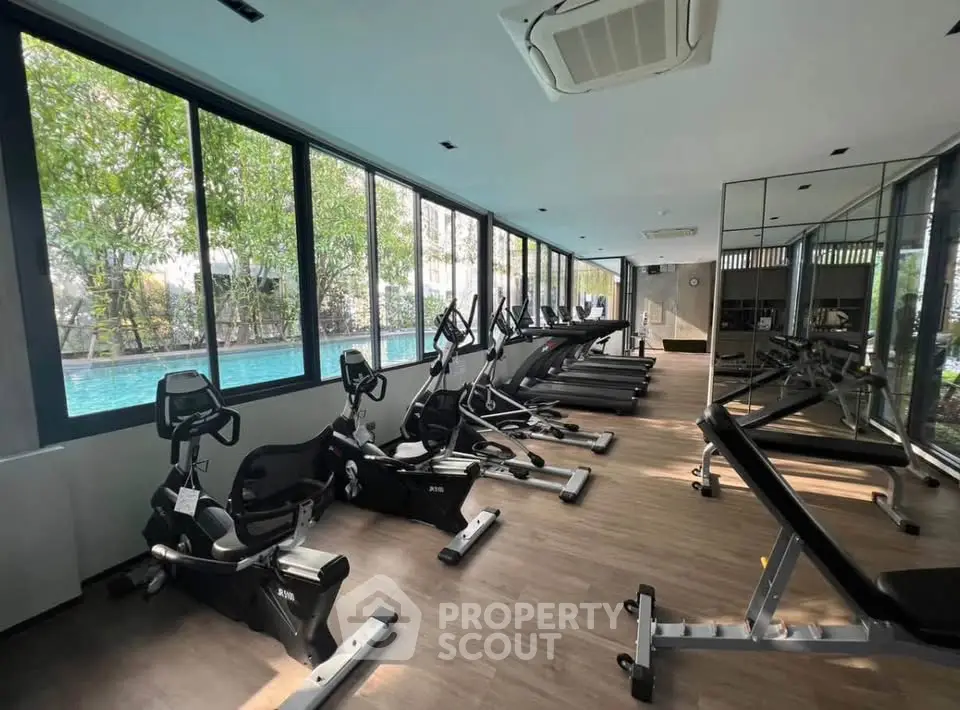 Modern gym with state-of-the-art equipment and pool view in luxury residential building.