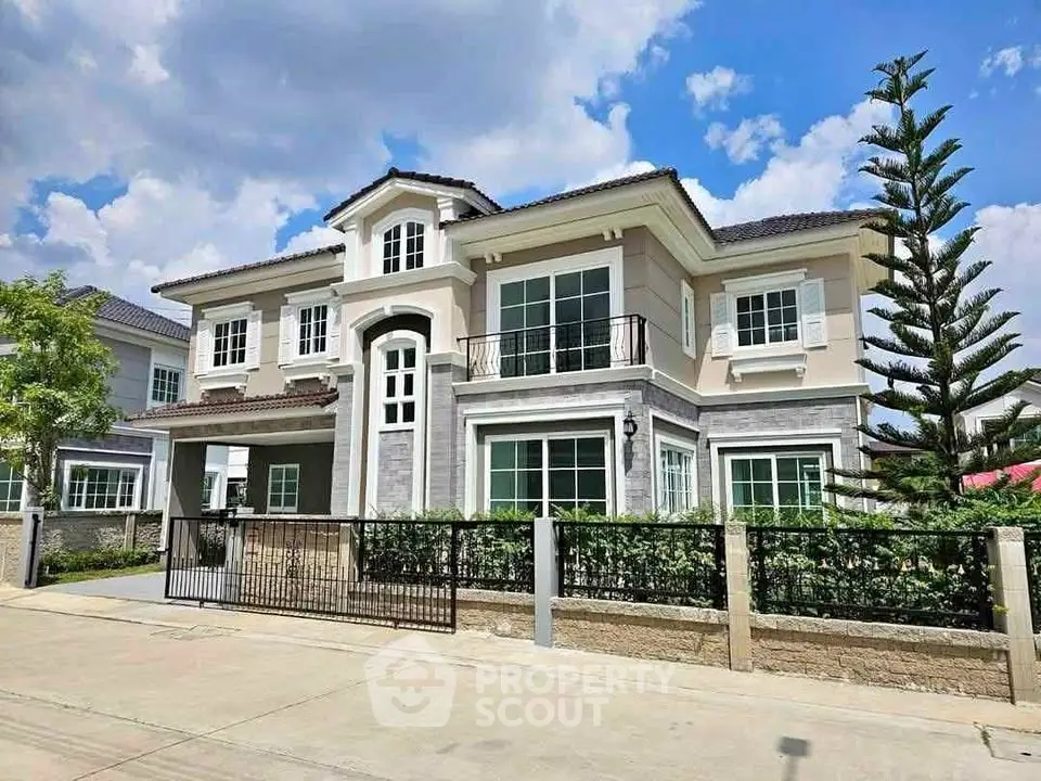 Elegant two-story house with modern design and lush landscaping under a clear blue sky.