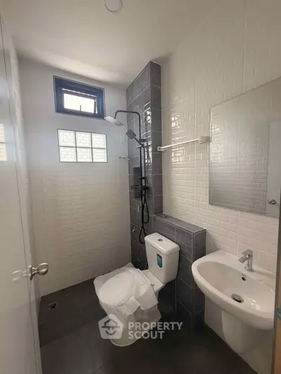Modern bathroom with sleek fixtures and stylish tile design, featuring a shower and compact layout.