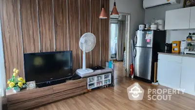 Modern living room with wooden flooring, stylish TV unit, and compact kitchen area.