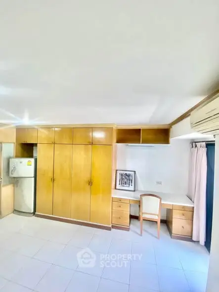 Spacious bedroom with built-in wooden wardrobe and study desk, featuring air conditioning and natural light.