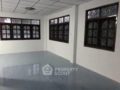 Spacious empty room with tiled floor and large windows, ideal for customization.