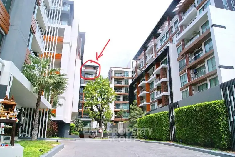 Modern apartment complex with lush greenery and spacious balconies in a vibrant urban setting.