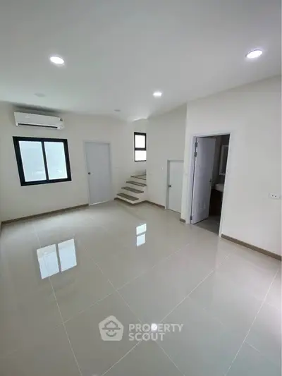 Spacious modern living room with sleek tile flooring and natural light.