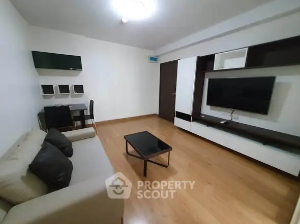Modern living room with sleek furniture and wall-mounted TV in a cozy apartment.
