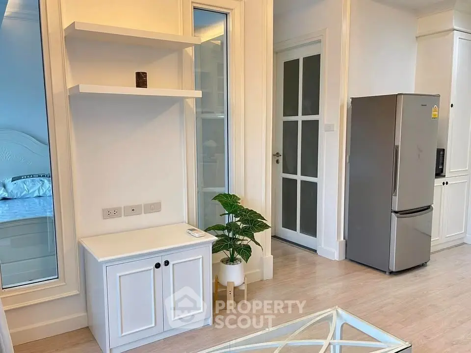 Modern interior with sleek kitchen and stylish decor, featuring a stainless steel fridge and elegant shelving.