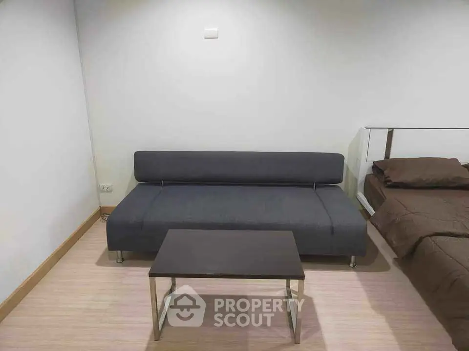 Modern minimalist living area with sleek sofa and table next to cozy bed
