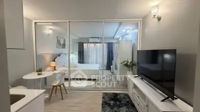 Modern studio apartment with glass partition, cozy bedroom, and stylish living area.