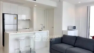 Modern open-layout kitchen and living room with sleek white design and cozy gray sofa.