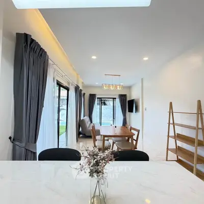 Modern open-plan living room with elegant dining area and large windows for natural light.