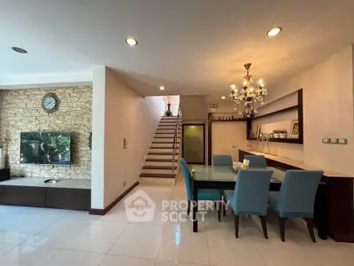Elegant living room with modern decor and dining area, featuring a stylish chandelier and stone accent wall.