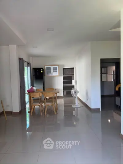 Spacious open-plan living area with dining set and modern kitchen appliances.