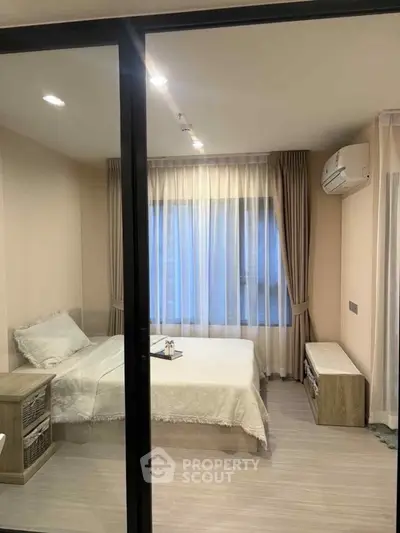 Cozy bedroom with modern decor and large window, featuring soft lighting and elegant curtains.