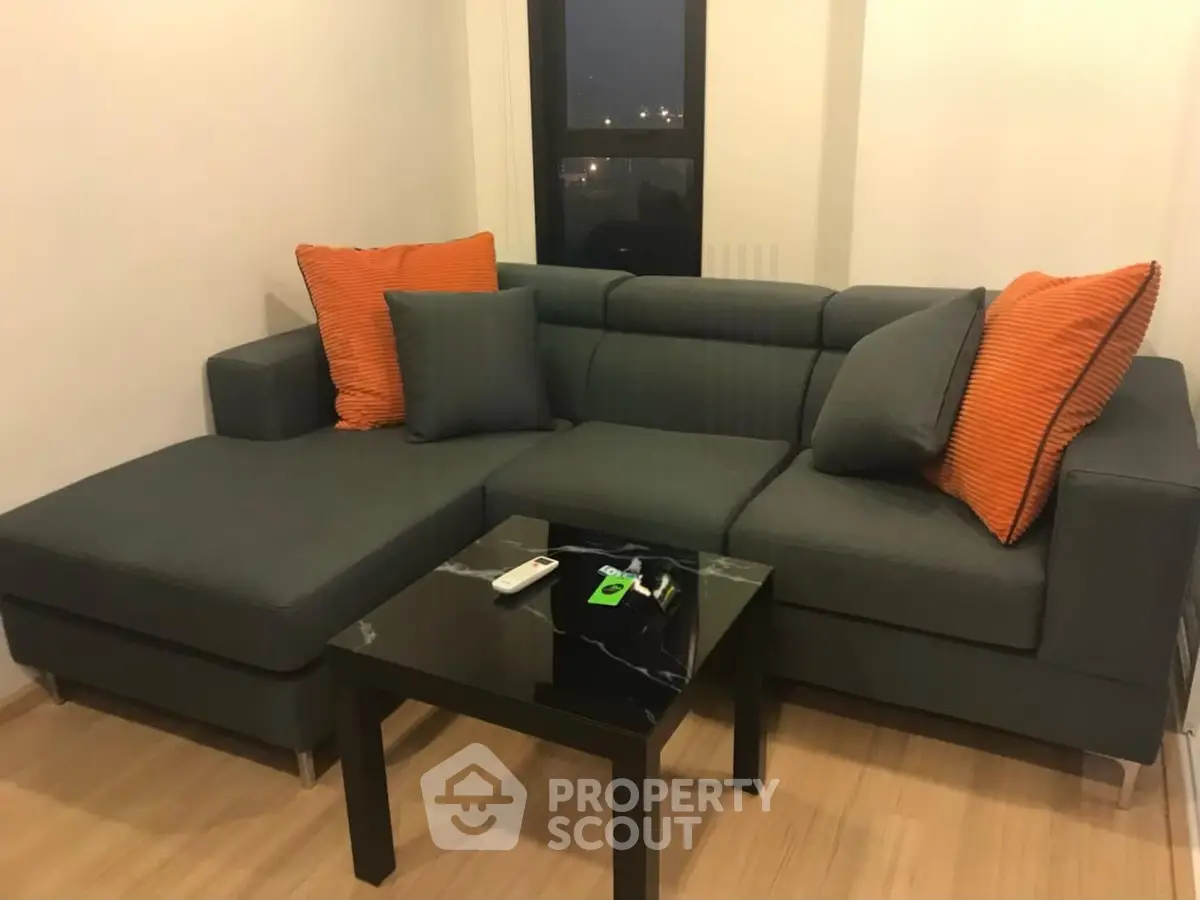 Modern living room with stylish gray sectional sofa and vibrant orange cushions.