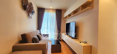 Modern living room with stylish decor, large TV, and natural light through floor-to-ceiling windows.