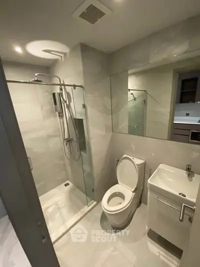 Modern bathroom with glass shower and sleek fixtures in a contemporary apartment.