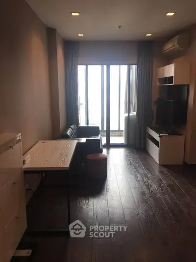 Modern living room with sleek furniture and large windows leading to a balcony, offering ample natural light.