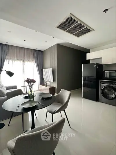 Modern living room with dining area, featuring sleek furniture and appliances, perfect for urban living.