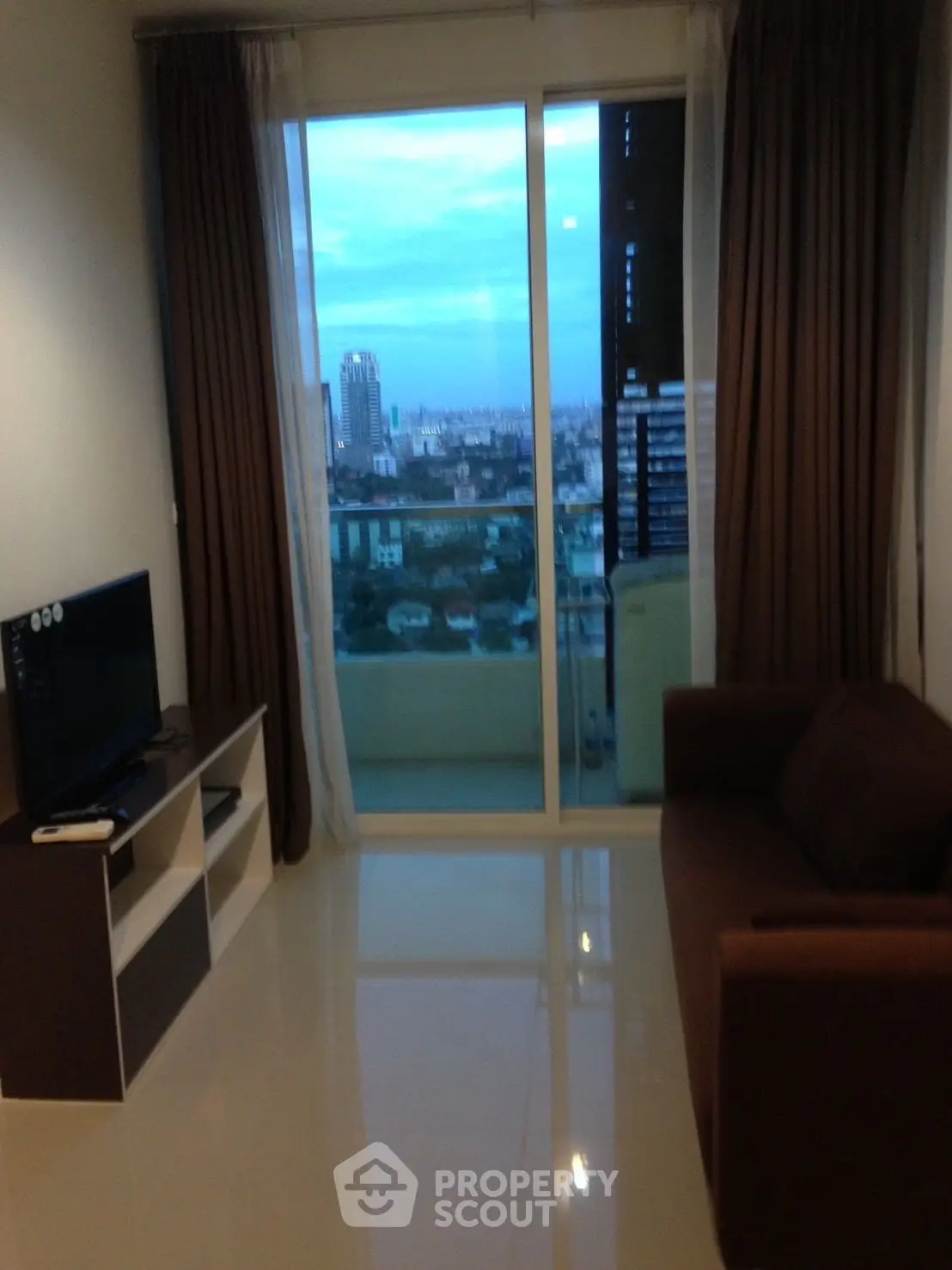 Modern living room with city view, sleek furniture, and large windows for natural light.
