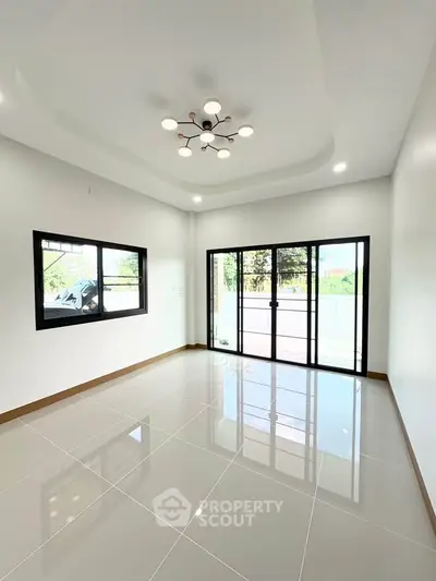 Spacious modern living room with large windows and elegant lighting, perfect for natural light and comfort.