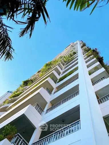 Stunning high-rise building with lush greenery and clear blue sky view.