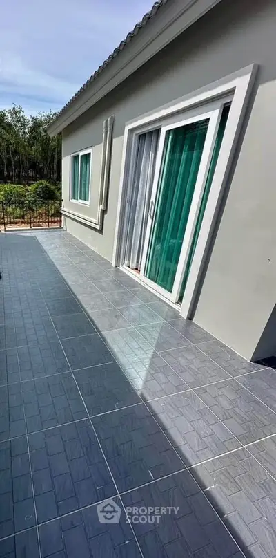 Modern house exterior with sliding glass doors and spacious tiled patio