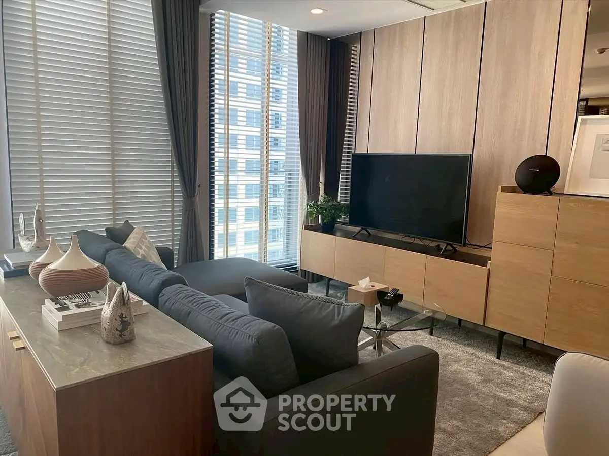 Modern living room with sleek furniture and large windows offering city views.