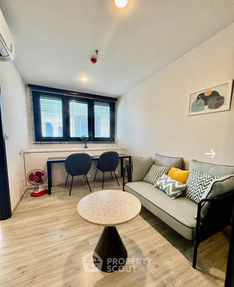 Modern living room with stylish decor and natural light, featuring a cozy sofa and workspace.