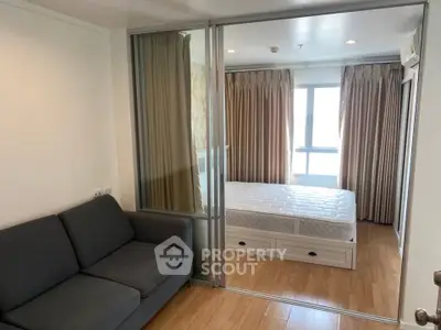 Modern bedroom with sliding glass doors and cozy sofa, featuring natural light and wooden flooring.