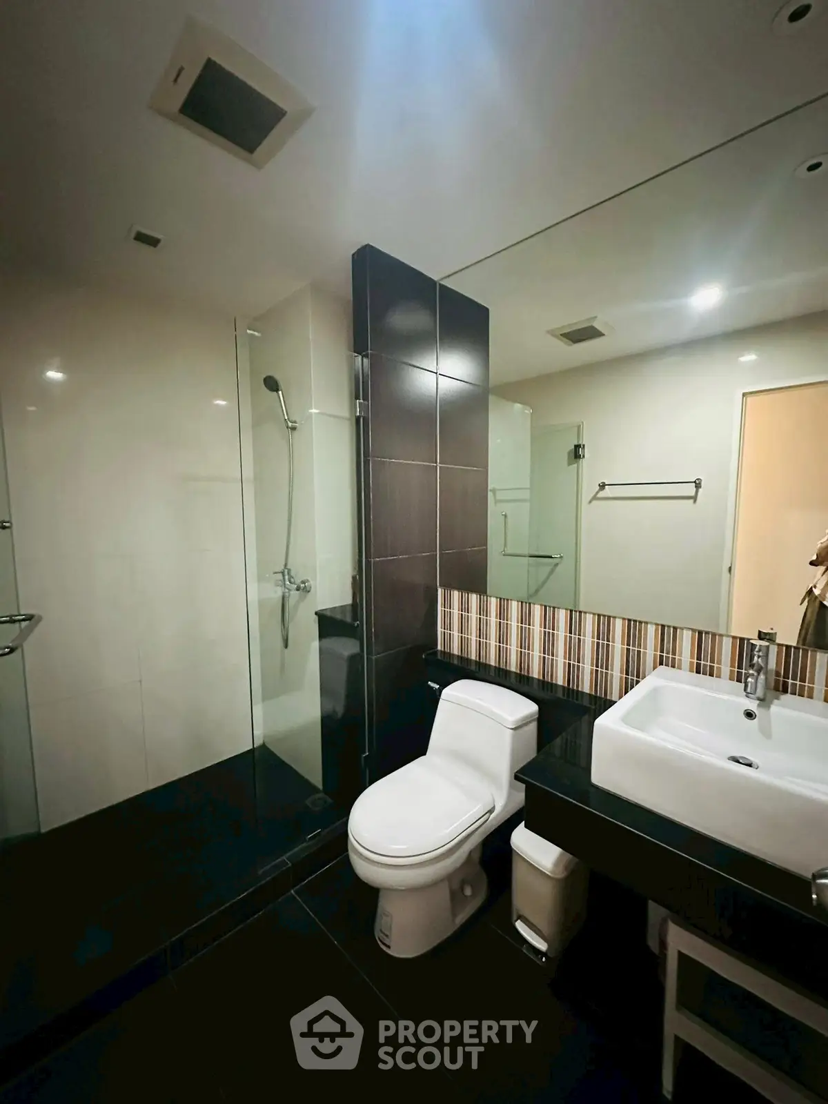 Modern bathroom with sleek design, featuring a glass shower and contemporary fixtures.
